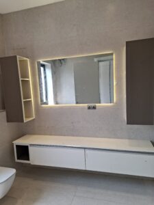 Minimalist master bathroom featuring a white floating vanity, large rectangular mirror, and warm recessed lighting.